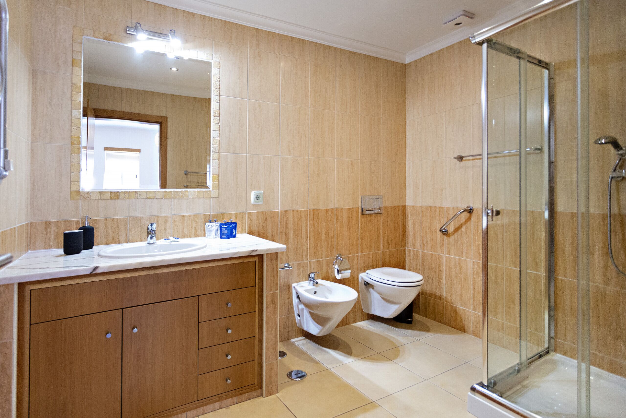 Une salle de bain moderne avec une douche à parois de verre, un meuble-lavabo à deux vasques et des toilettes.