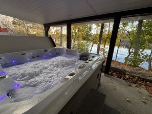 A hot tub with a view of a lake and trees.