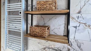 A bathroom with a marble wall, a wooden shelf unit, and a white towel rack. - Lavanda Penthouse - Three Bedroom Apartment (Kastel Luksic)