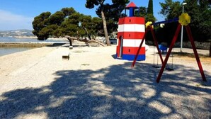A beach with a red and white striped lighthouse, trees, and a clear sky. - Lavanda Penthouse - Three Bedroom Apartment (Kastel Luksic)