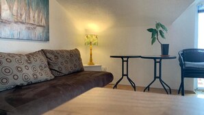 A cozy room with a brown sofa, a small round table, a lamp, and a potted plant.