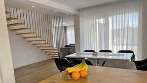 Un espace repas moderne avec une table en bois, un panier de fruits et un escalier avec des marches en bois.