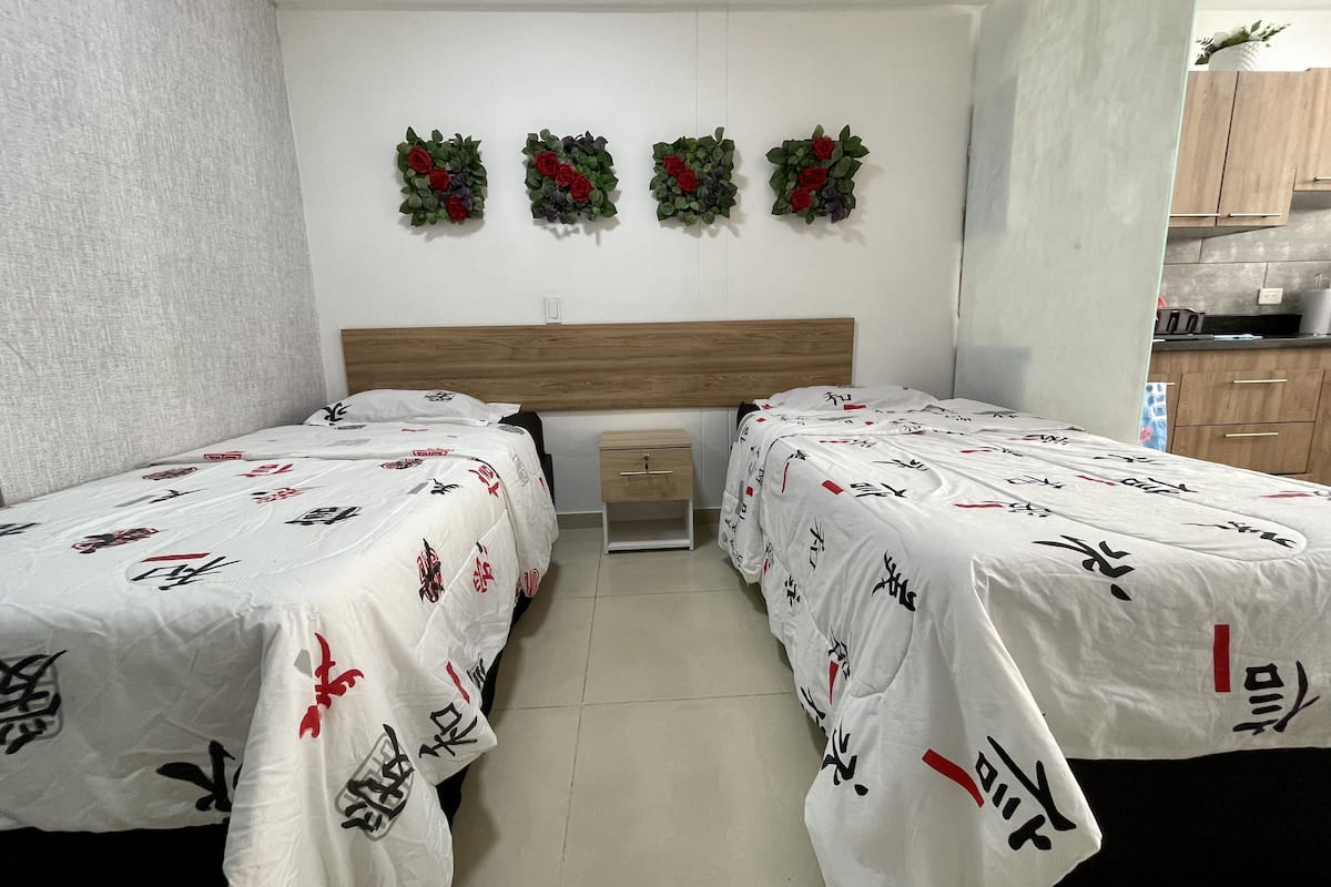 A hotel room with two beds, a wooden headboard, a small bedside table, and a wall-mounted shelf.