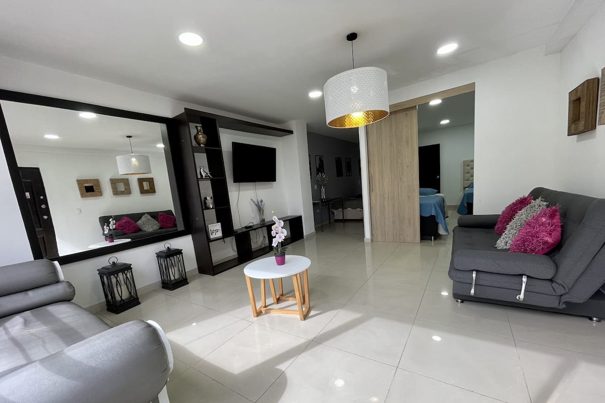 A modern living room with a grey sofa, a white coffee table, and a large mirror.