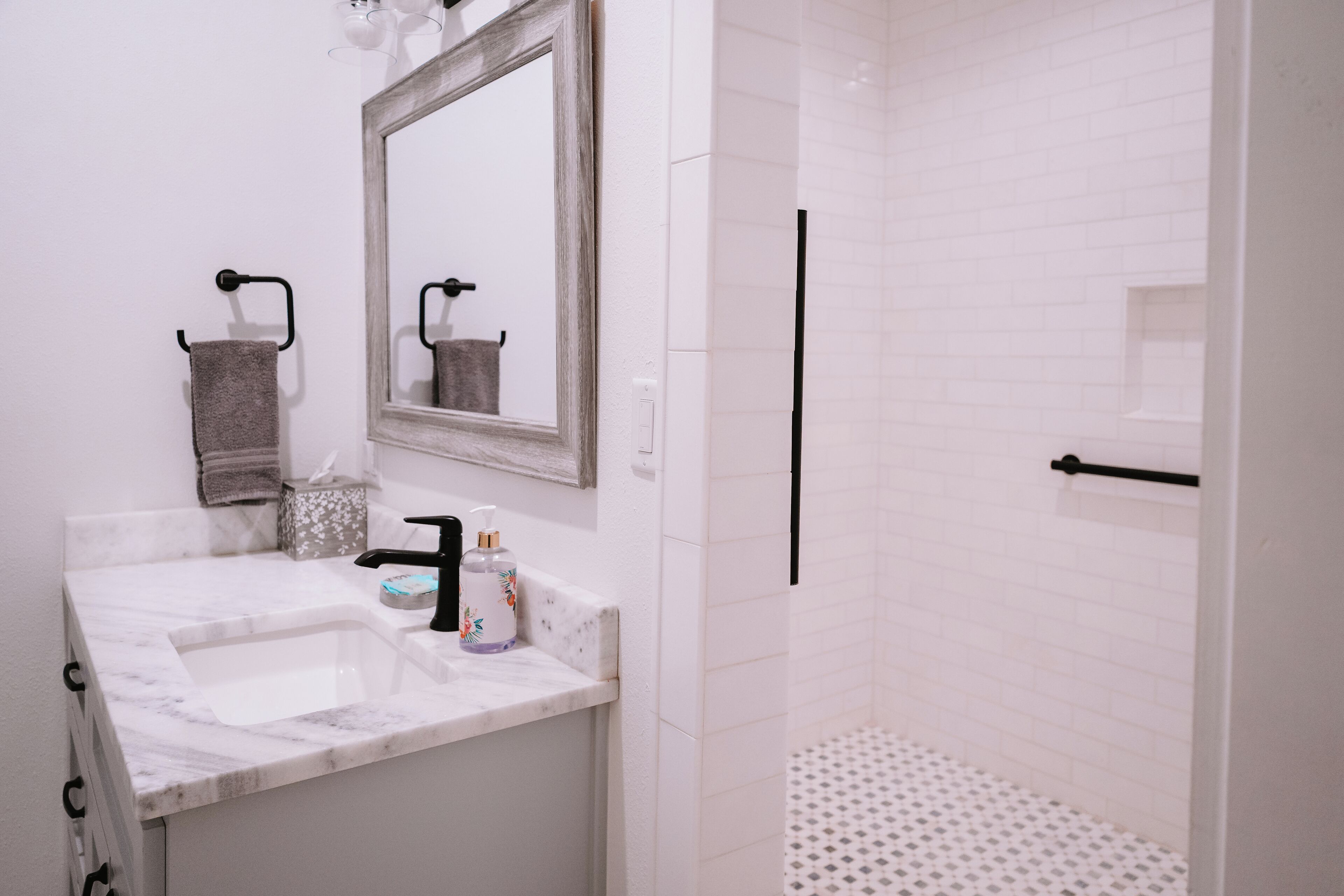 A bathroom with a marble sink, a mirror, a towel rack, and a shower area.