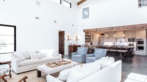 A spacious living room with a white sofa, blue armchairs, and a dining area with a wooden table and chairs. - Lone Star River Ranch- Large Luxury Venue for Conferences & Retreats - sleeps 44 (Brady)