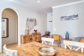 A dining area with a wooden table, white chairs, and a decorative bowl. There is a wooden cabinet with a vase and a picture frame on the wall. - LA BELLESA: Beautiful house with private pool in l'Escala (L'Escala)
