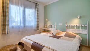 A bedroom with a bed, a bedside table, a lamp, and a window with curtains. - LA BELLESA: Beautiful house with private pool in l'Escala (L'Escala)