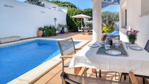 A poolside area with a table set for two, a chair, and a small table with a coffee pot and cups. - LA BELLESA: Beautiful house with private pool in l'Escala (L'Escala)