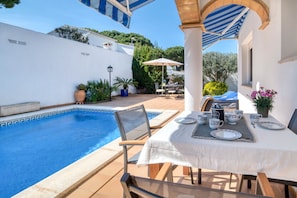 A poolside area with a table set for two, a chair, and a small table with a coffee pot and cups. - LA BELLESA: Beautiful house with private pool in l'Escala (L'Escala)