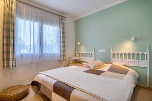 A bedroom with a bed, a bedside table, a lamp, and a window with curtains. - LA BELLESA: Beautiful house with private pool in l'Escala (L'Escala)