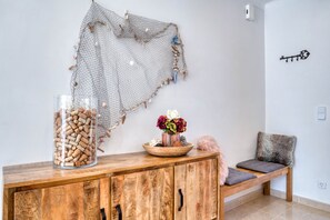A wooden cabinet with a glass jar of corks, a decorative bowl with flowers, and a woven wall hanging. - LA BELLESA: Beautiful house with private pool in l'Escala (L'Escala)