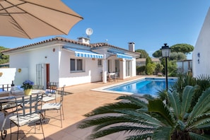 A villa with a swimming pool, outdoor seating, and a large umbrella. - LA BELLESA: Beautiful house with private pool in l'Escala (L'Escala)