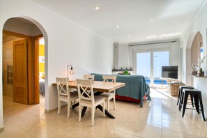 A modern kitchen with a dining area, wooden chairs, a table, and a TV. - LA BELLESA: Beautiful house with private pool in l'Escala (L'Escala)
