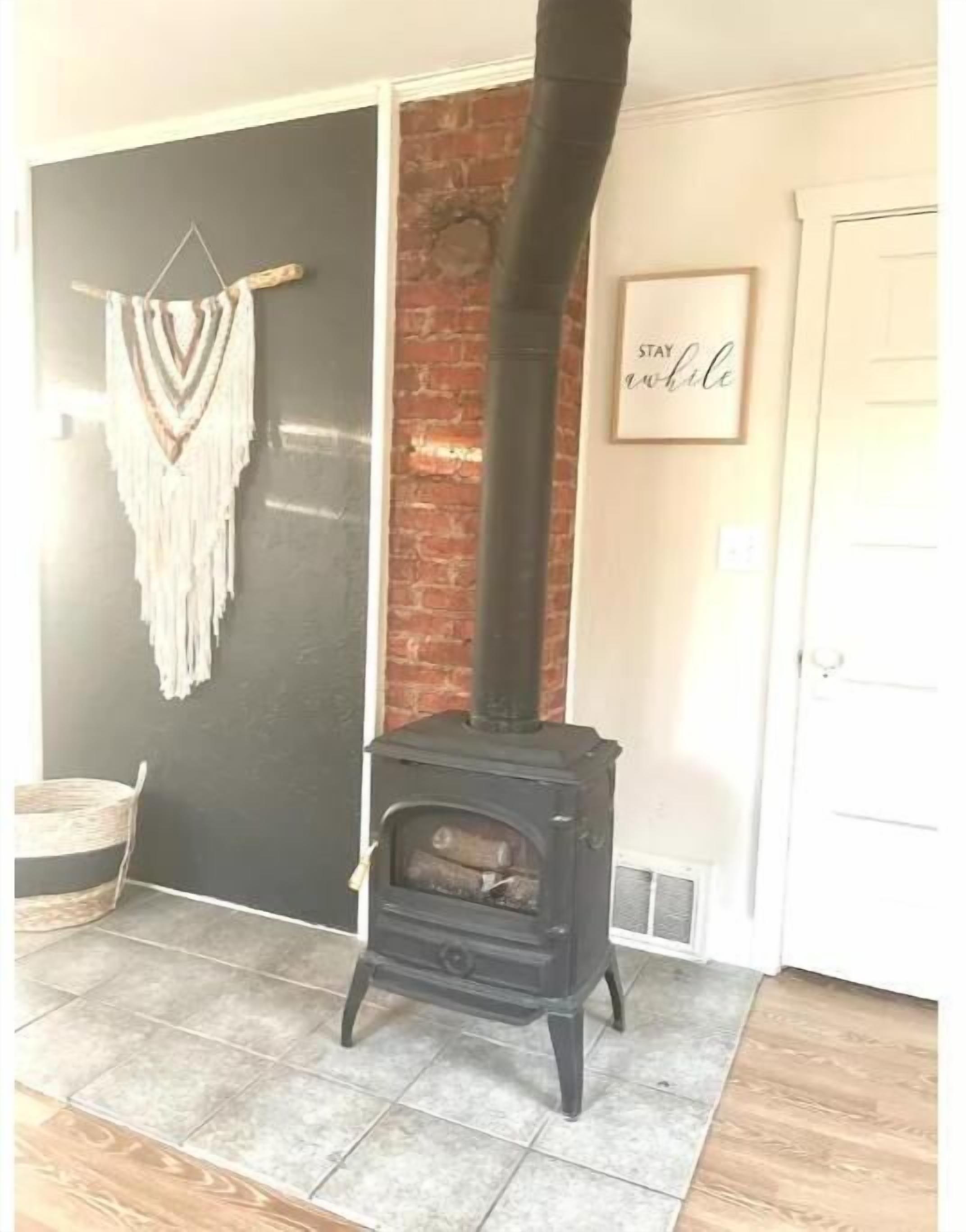 A black wood-burning stove in a room with a black wall and a white door.