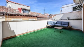 A rooftop terrace with a green artificial turf, a blue sofa, and a wooden table. - Ático del Oso · Terraza privada en Lavapiés (Madrid)