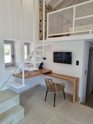 Stylish space with a white staircase, wooden desk, and flat-screen TV.
