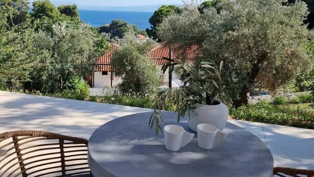 A covered outdoor seating area with a view of the sea and olive trees. - Stone build Suite with private small pool (Skiathos)