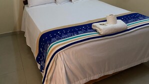 A neatly made bed with white linens, a dark wooden headboard, and a blue patterned throw blanket.