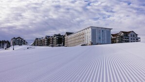 Et snedækket skiområde med flere bygninger, heriblandt et stort hotel med fladt tag og en mindre bygning med saddeltag.