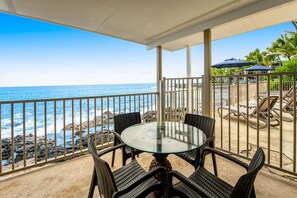 Relax in this ocean-view seating area with a glass-top table and wicker chairs, surrounded by umbrellas for dining or relaxation.