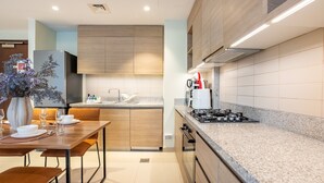 Una cocina moderna con armarios de madera, encimera de granito, zona de comedor con mesa y sillas, y estufa empotrada.