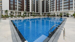 Un edificio moderno con una piscina central rodeada de sillones de descanso y plantas en macetas.