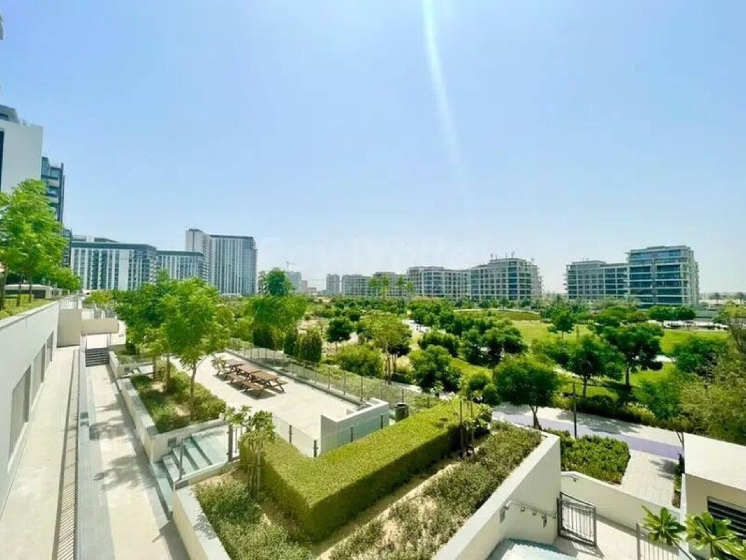 A residential area with modern buildings, a well-maintained lawn, and a clear sky.