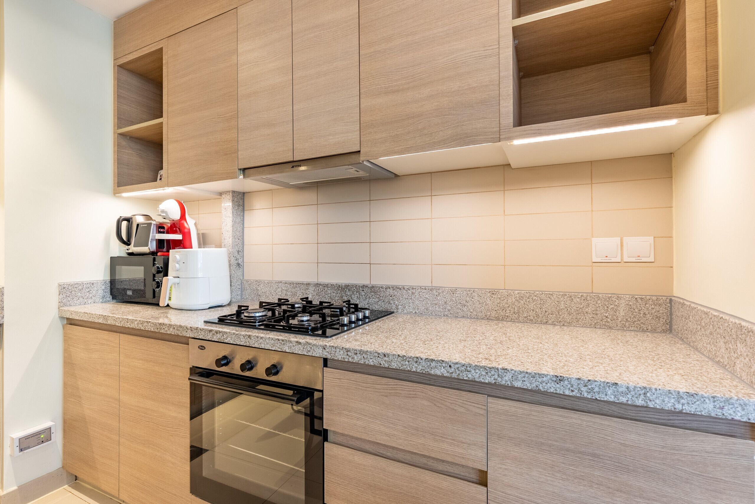 Eine moderne Küche mit Holzschränken, einem Gasherd, einem Backofen und einer Mikrowelle.
