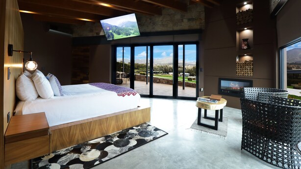Un dormitorio moderno con una cama grande, un televisor y vistas al exterior.