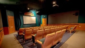 Ein Kino mit mehreren Sitzreihen, einer Leinwand und einer Projektionskabine.