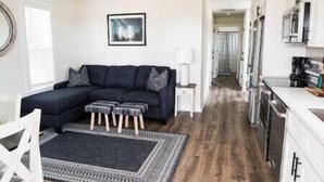 Un salon moderne avec un canapé foncé, un plancher en bois et un ventilateur de plafond.