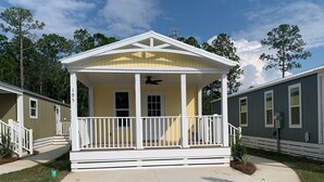 A single-story mobile home with a porch, a small front yard, and a neighboring mobile home.