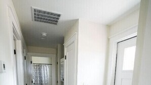 A hallway with wooden flooring, white walls, and doors leading to other rooms.