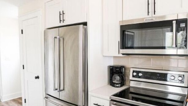 A modern kitchen with stainless steel appliances, white cabinetry, and a wood floor. - Short drive to the beautiful 30-A beaches!!
Cozy Riverwalk Landing Cottage 5-E (Freeport)