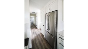 A kitchen with white cabinetry and a stainless steel refrigerator.