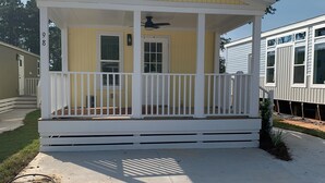 A single-story mobile home with a porch, a front door, and a small window.