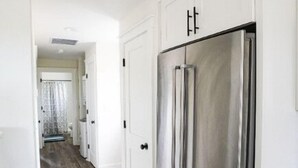 A kitchen with white cabinetry and a stainless steel refrigerator.