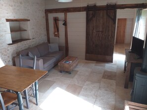 Una sala de estar acogedora con un sofá, una mesa de centro de madera, un televisor y una puerta corrediza que da a otra habitación.