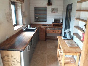 Cocina compacta con encimeras de madera, microondas integrado y ventana.