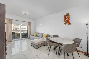 A modern living room with a grey sofa, a round table, and a decorative wall piece.