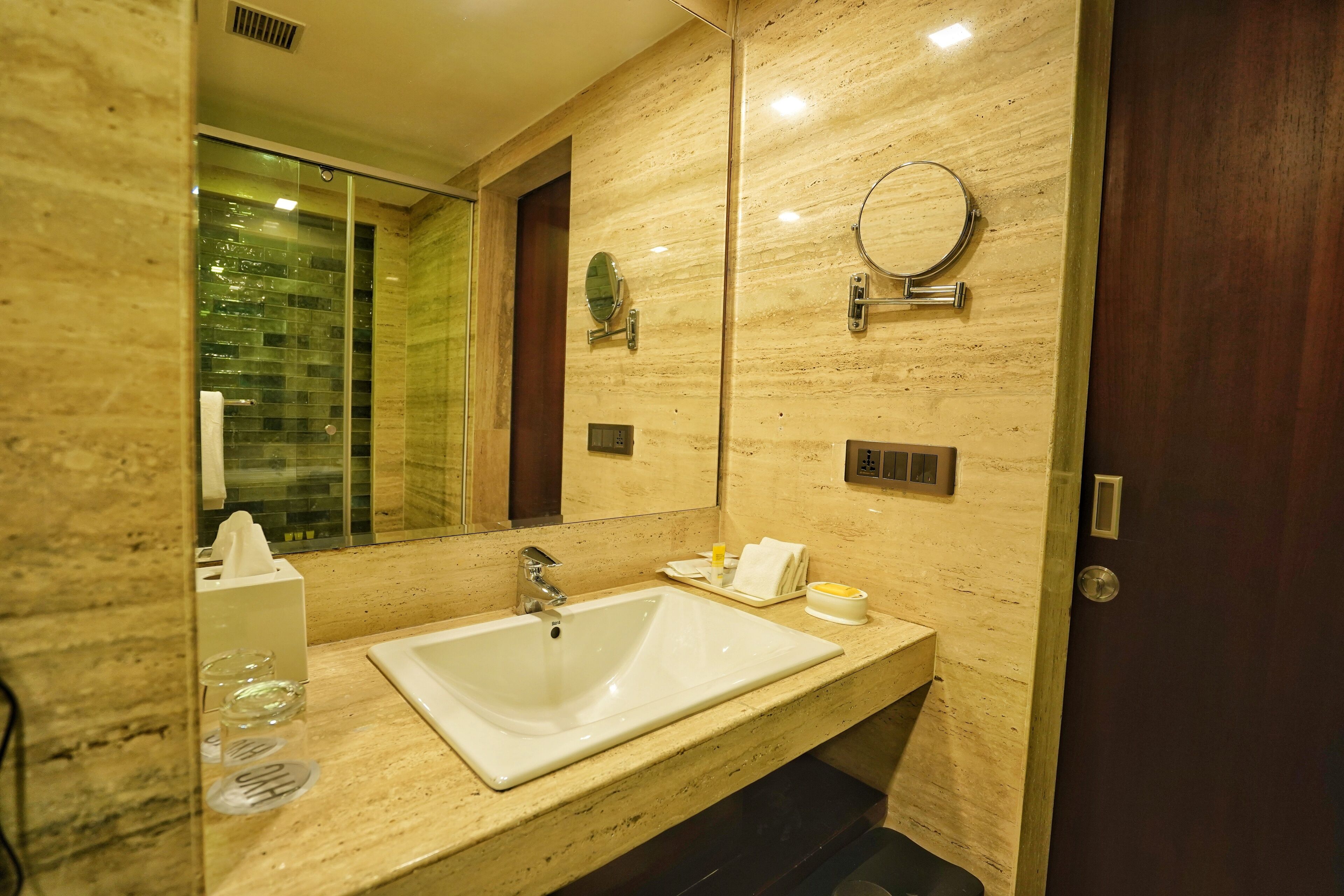 A modern bathroom with a large sink, mirror, and a glass shower enclosure.