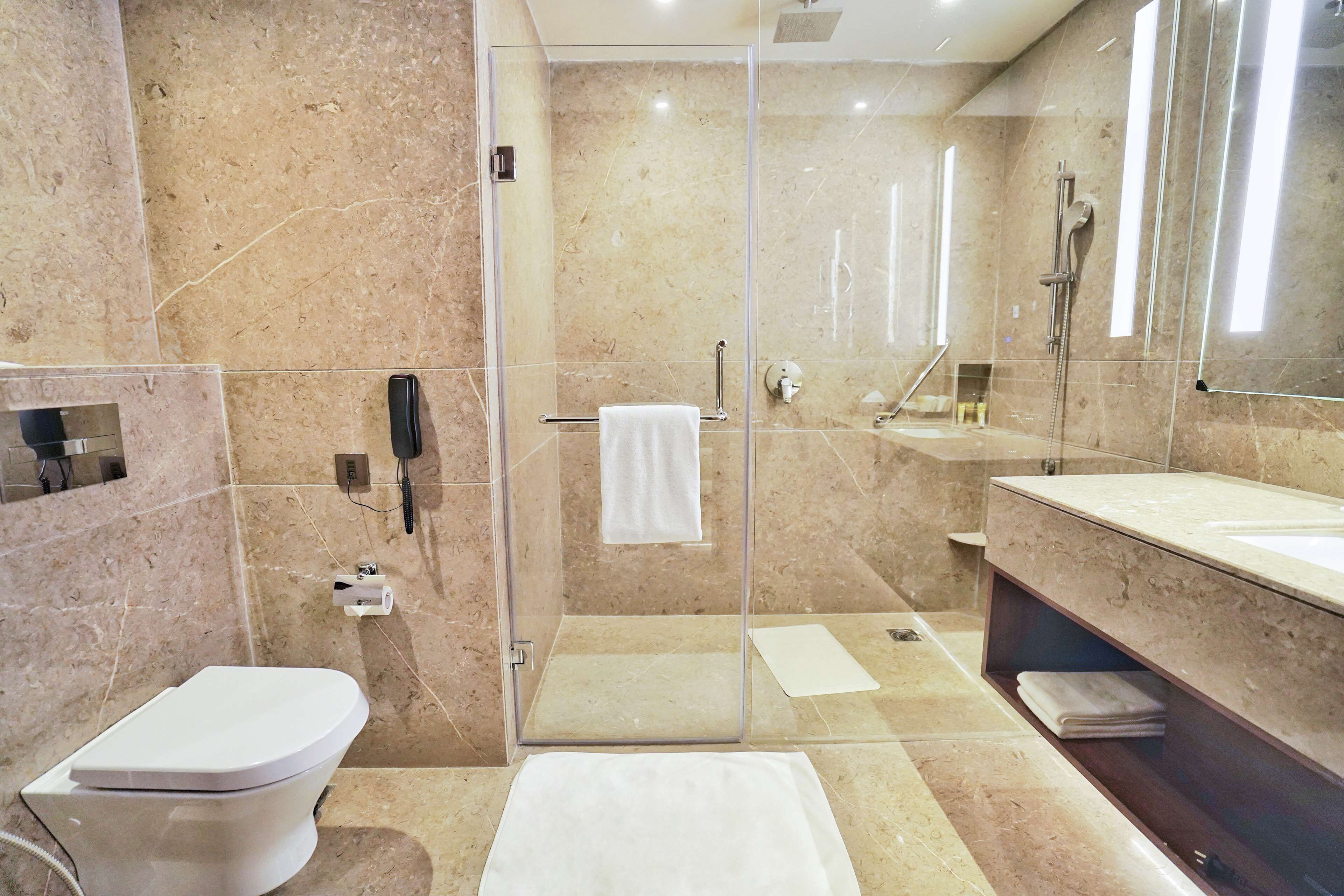 A modern bathroom with a glass-enclosed shower, a toilet, a sink, and a vanity with a mirror.