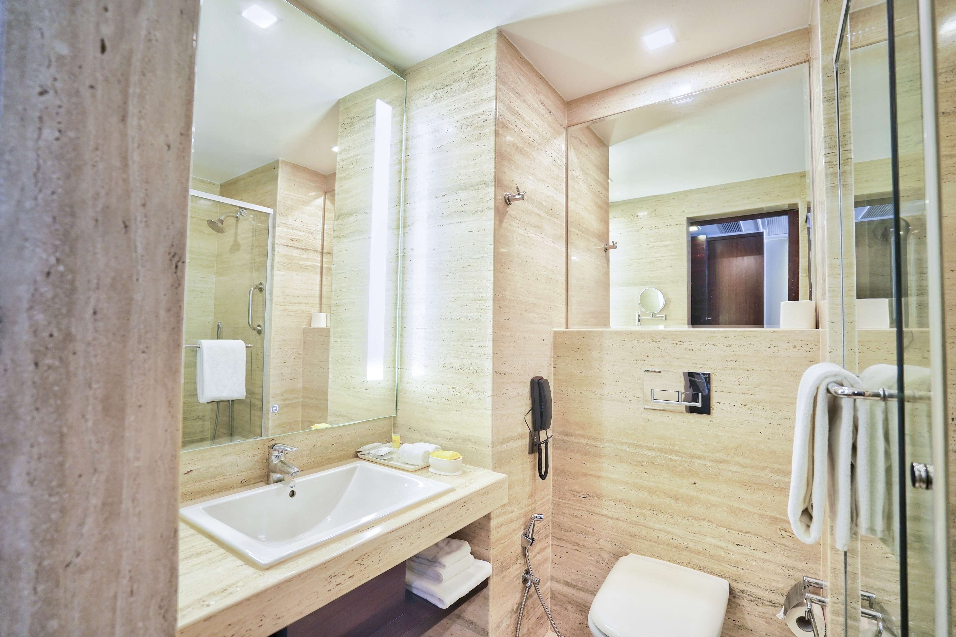 Une salle de bain moderne avec un grand lavabo, un miroir et une douche à l’italienne en verre.