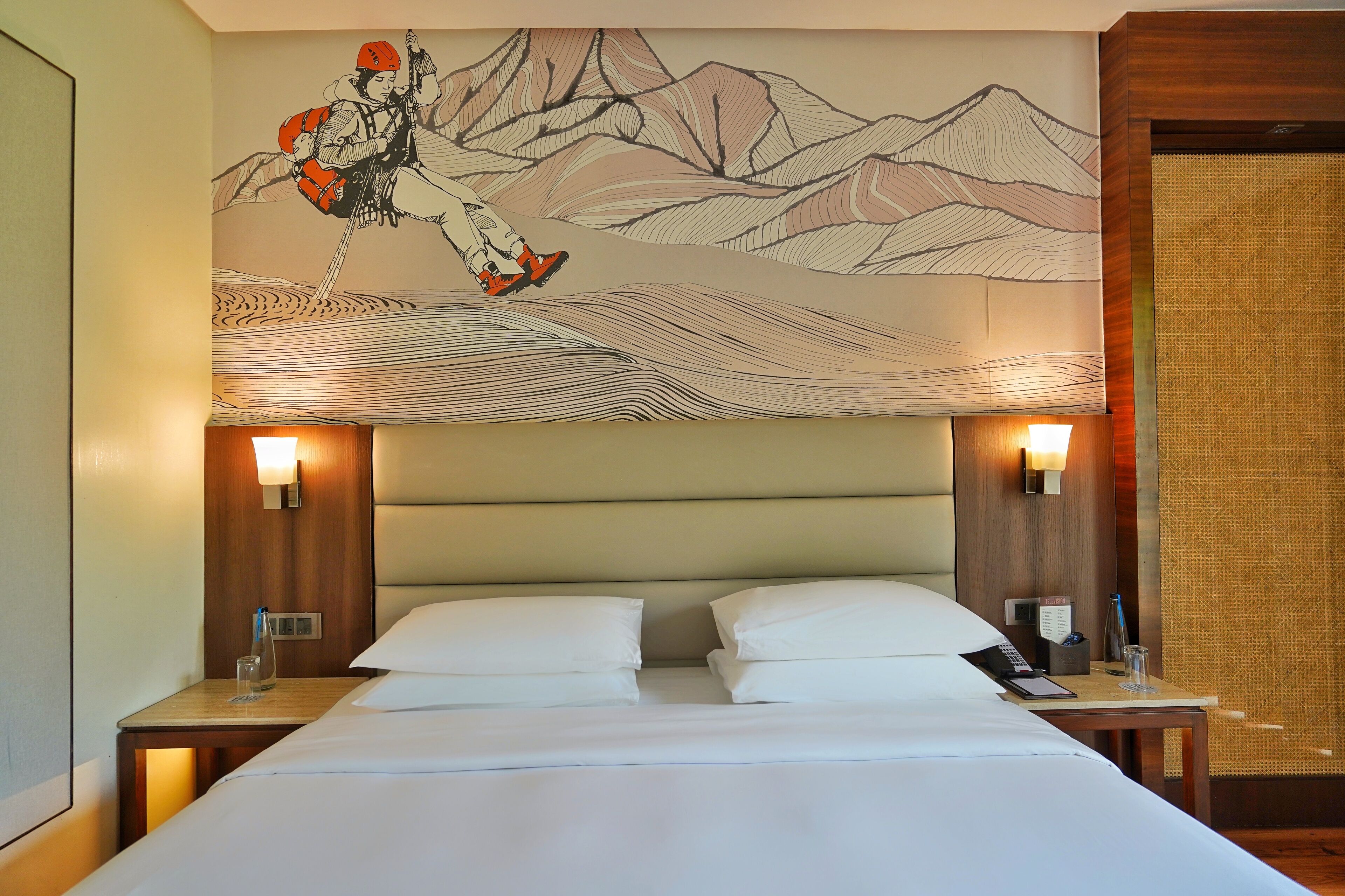 A hotel room with a bed, two bedside tables, a wall-mounted lamp, and a decorative wall piece.