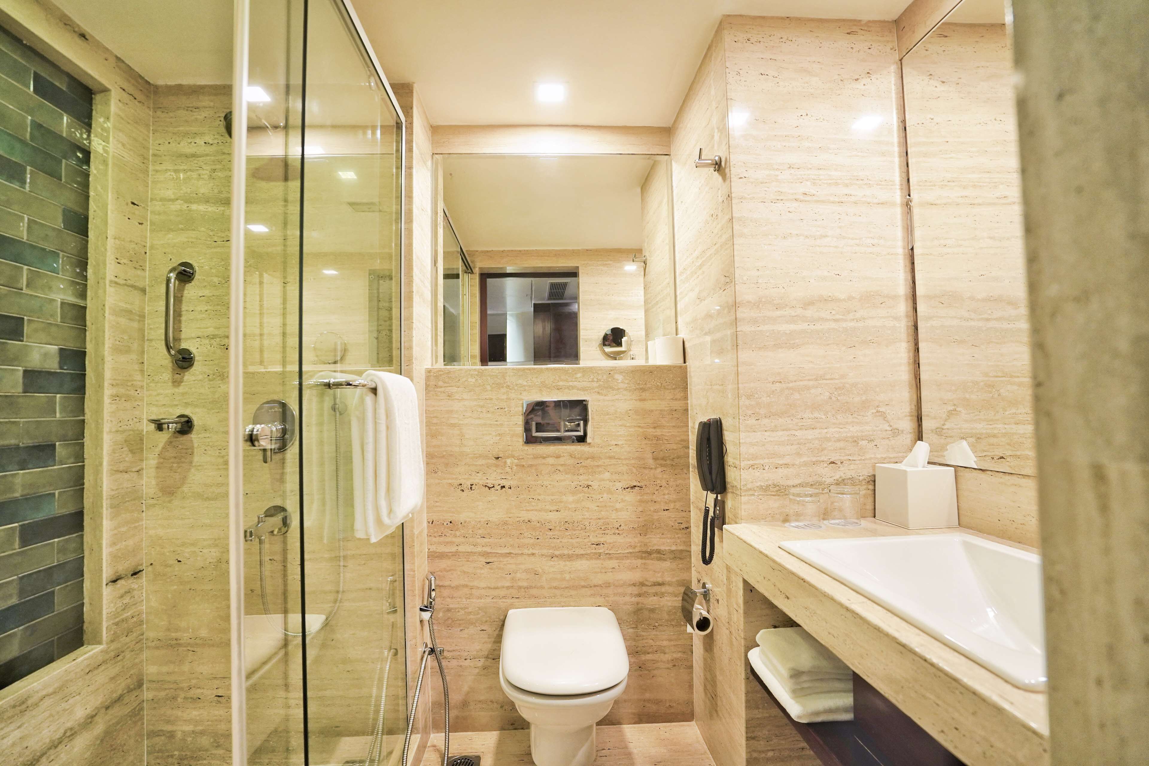 A modern bathroom with a glass-enclosed shower, a white toilet, and a large bathtub.