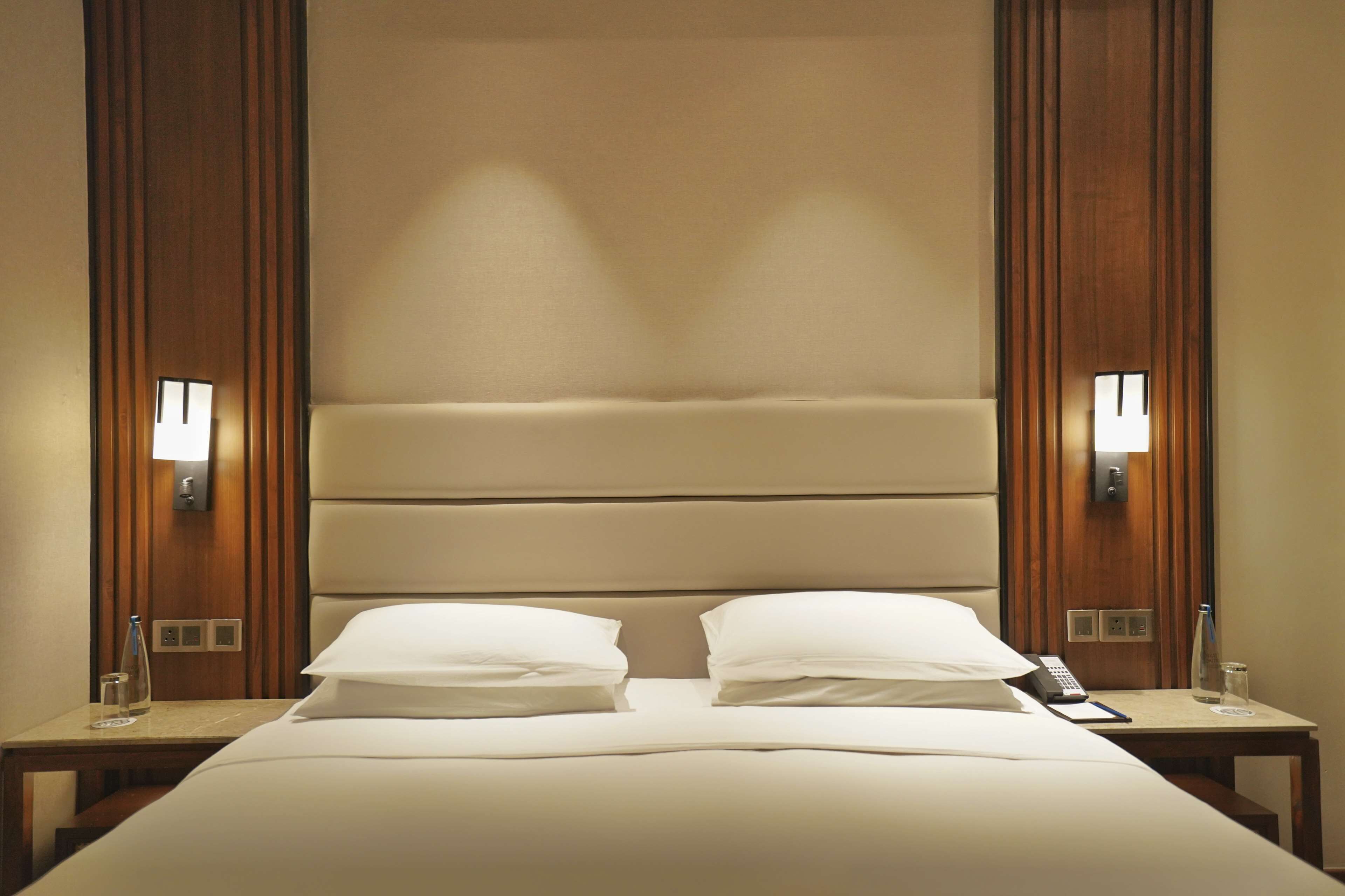 Ein Hotelzimmer mit einem großen Bett, zwei Nachttischen, einer Lampe und einem Telefon.