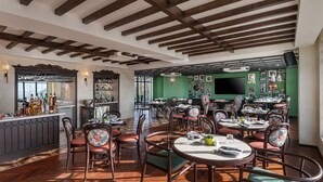 A spacious restaurant with wooden beams, a bar area, and a green wall adorned with pictures. - Hyatt Centric Rajpur Road Dehradun (Dehradun)