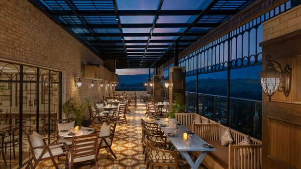 An outdoor dining area with tables and chairs, a patterned floor, and a view of the cityscape. - Hyatt Centric Rajpur Road Dehradun (Dehradun)