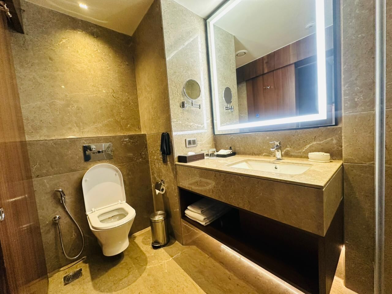 A modern bathroom with a toilet, sink, and mirror.
